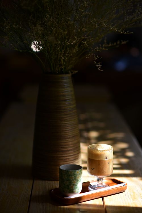 Free A cozy coffee scene featuring a wooden vase with flowers and a coffee setup on a wooden tray. Stock Photo