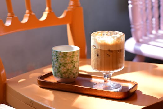 Warm sunlit scene with iced coffee and tea cup on a wooden tray. Perfect for cozy moments.
