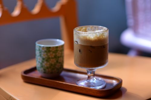 Free An elegant display of iced coffee and a patterned tea cup on a wooden tray indoors. Stock Photo