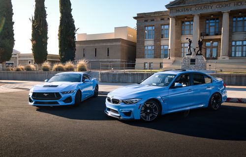 Free Two blue sports cars parked elegantly in front of a courthouse building, showcasing modern automotive design. Stock Photo