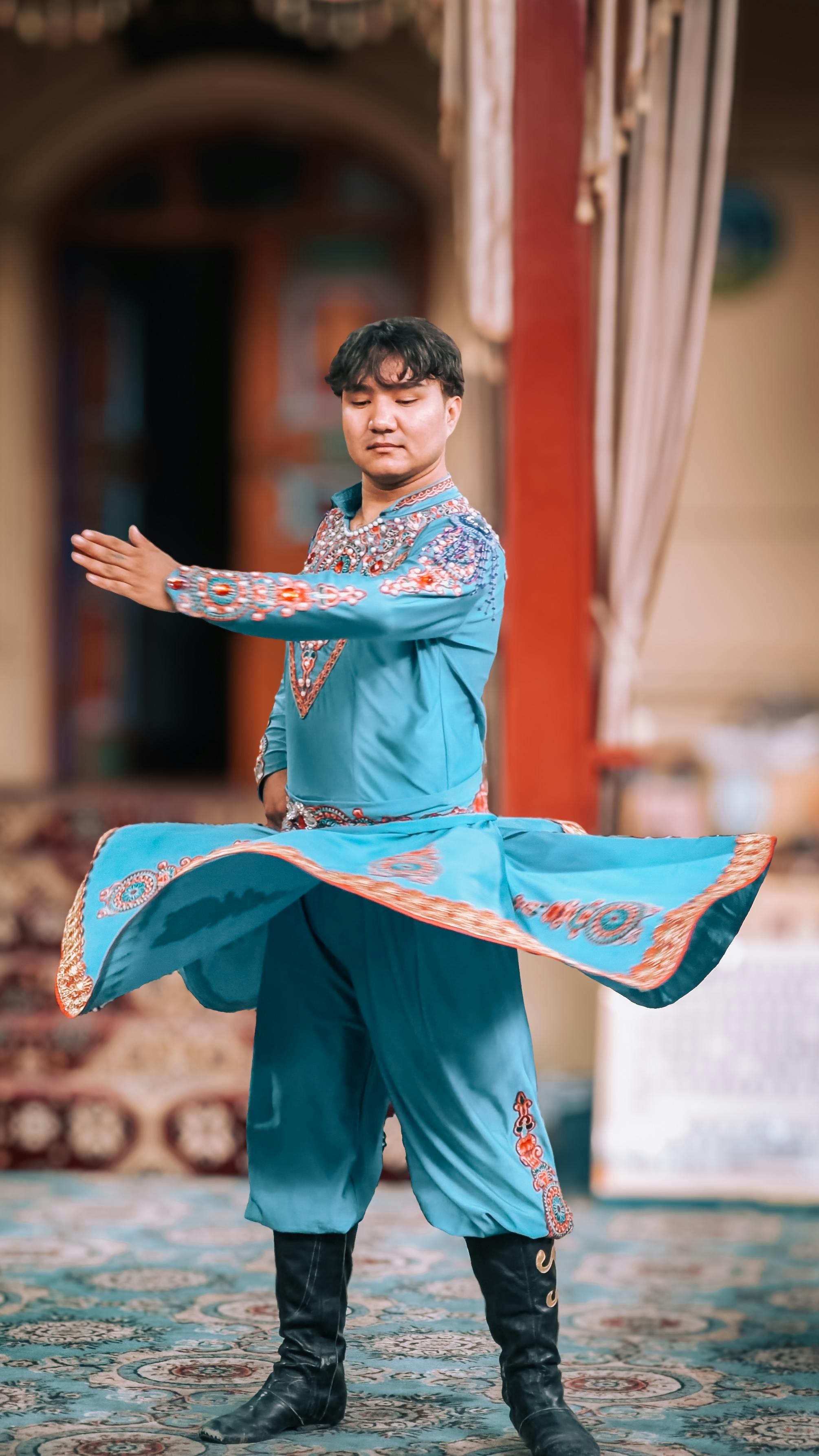A performer in bright cultural attire dances with energy in an indoor setting, showcasing traditional dance styles.
