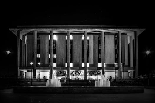 Monochrome image showcasing the National Library of Australia with illuminating fountains at night.