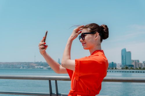 Free Woman in red dress taking selfie with city skyline in the background. Stock Photo