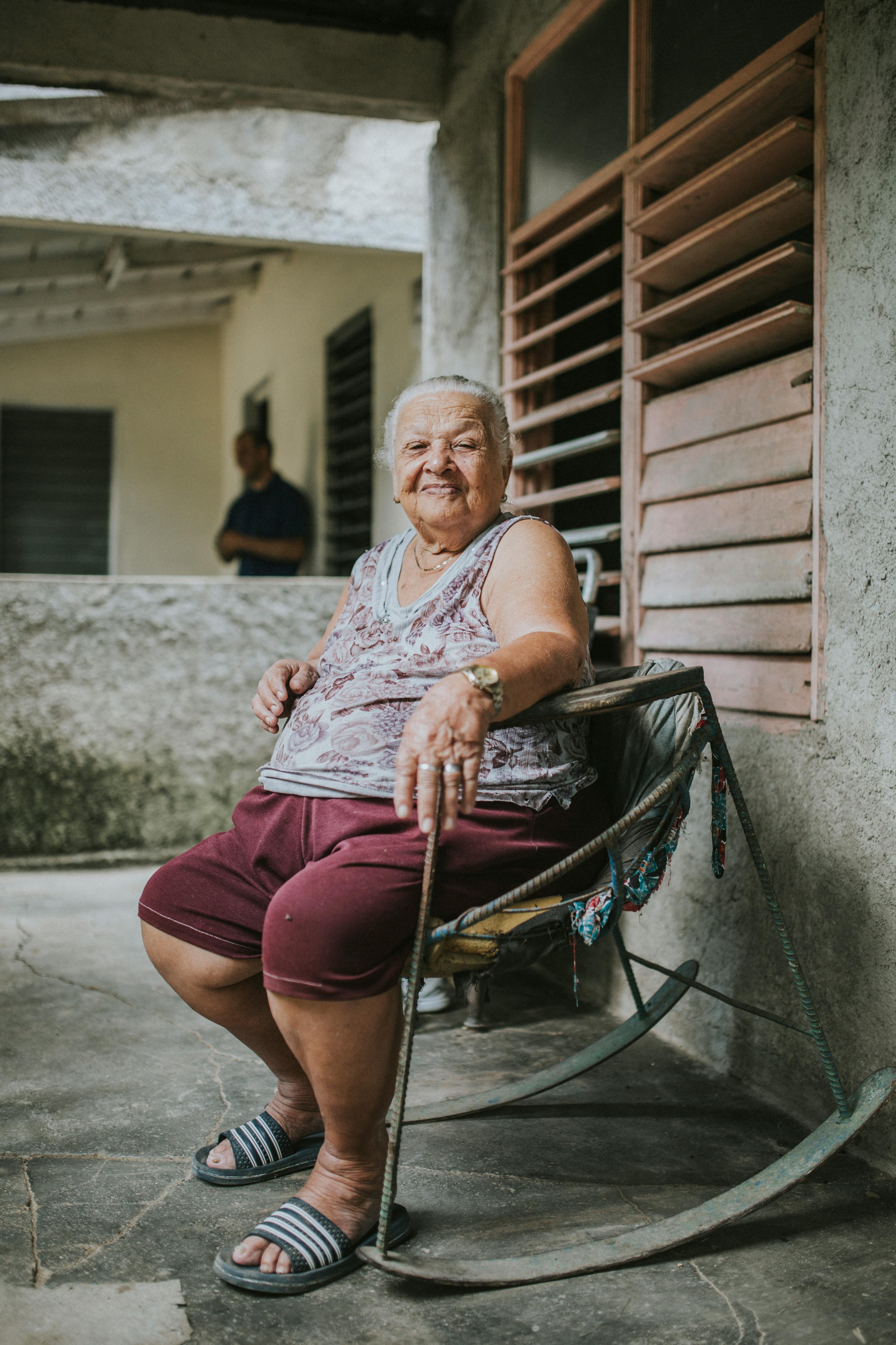 Senior woman sitting on a rustic chair in an outdoor setting, exuding warmth and wisdom.