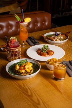 A delectable spread of gourmet dishes paired with vibrant cocktails at a stylish restaurant.
