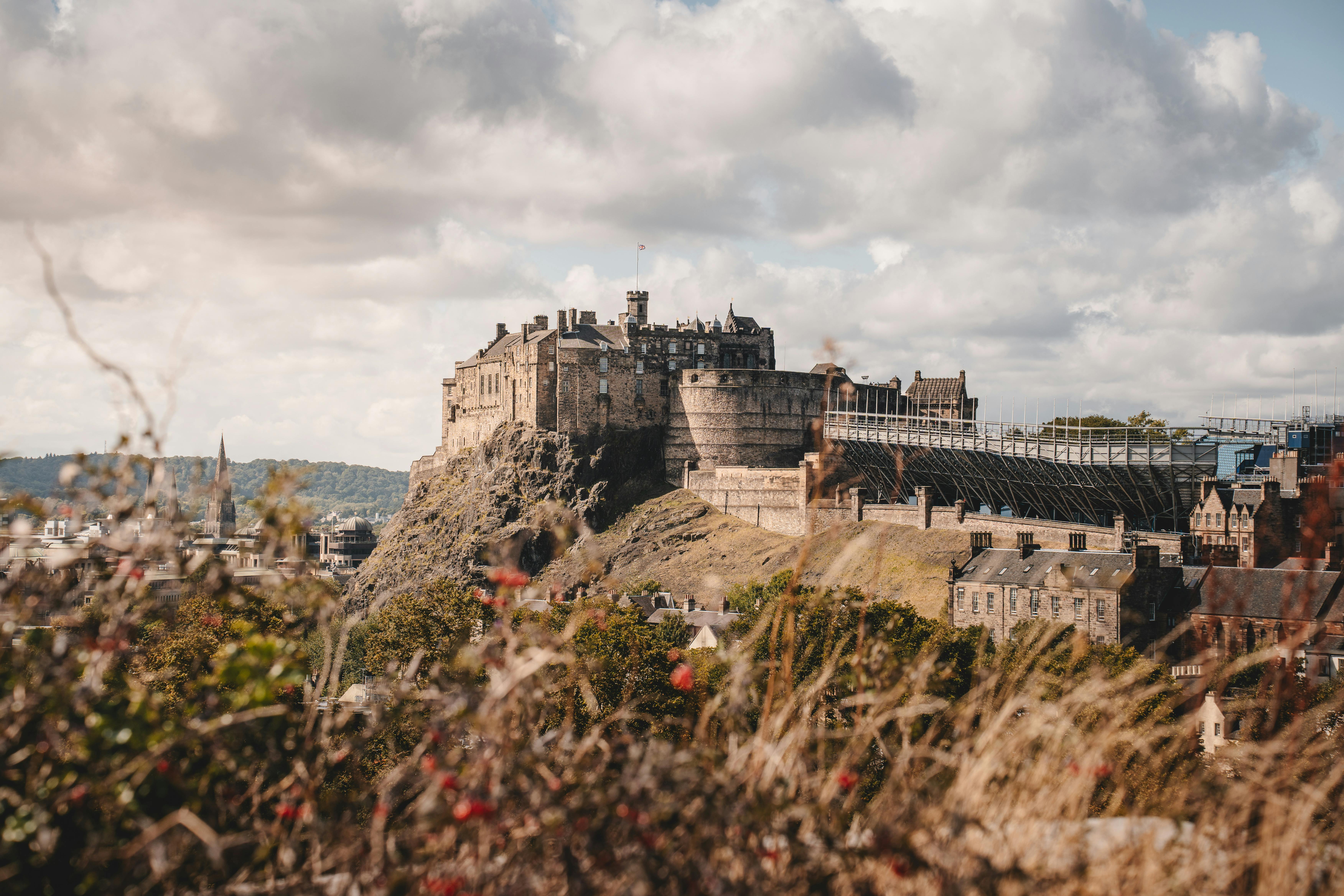 Breathtaking view of Edinburgh Castle surrounded by autumn foliage under a cloudy sky.