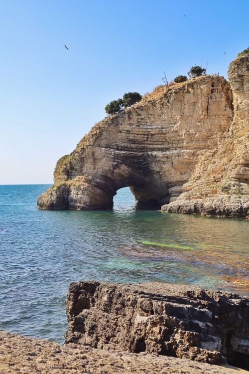 Free A breathtaking coastal scene featuring a natural rock arch over clear blue waters, ideal for travel imagery. Stock Photo