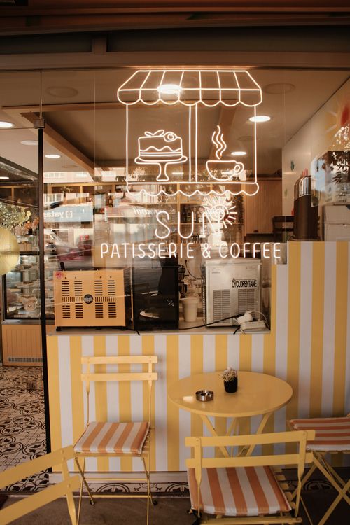 Free Charming outdoor cafe with a neon sign displaying desserts and coffee on a sunny day. Stock Photo
