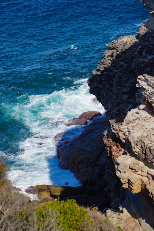 Free Stunning coastal view with cliffs and crashing waves in bright sunlight. Stock Photo