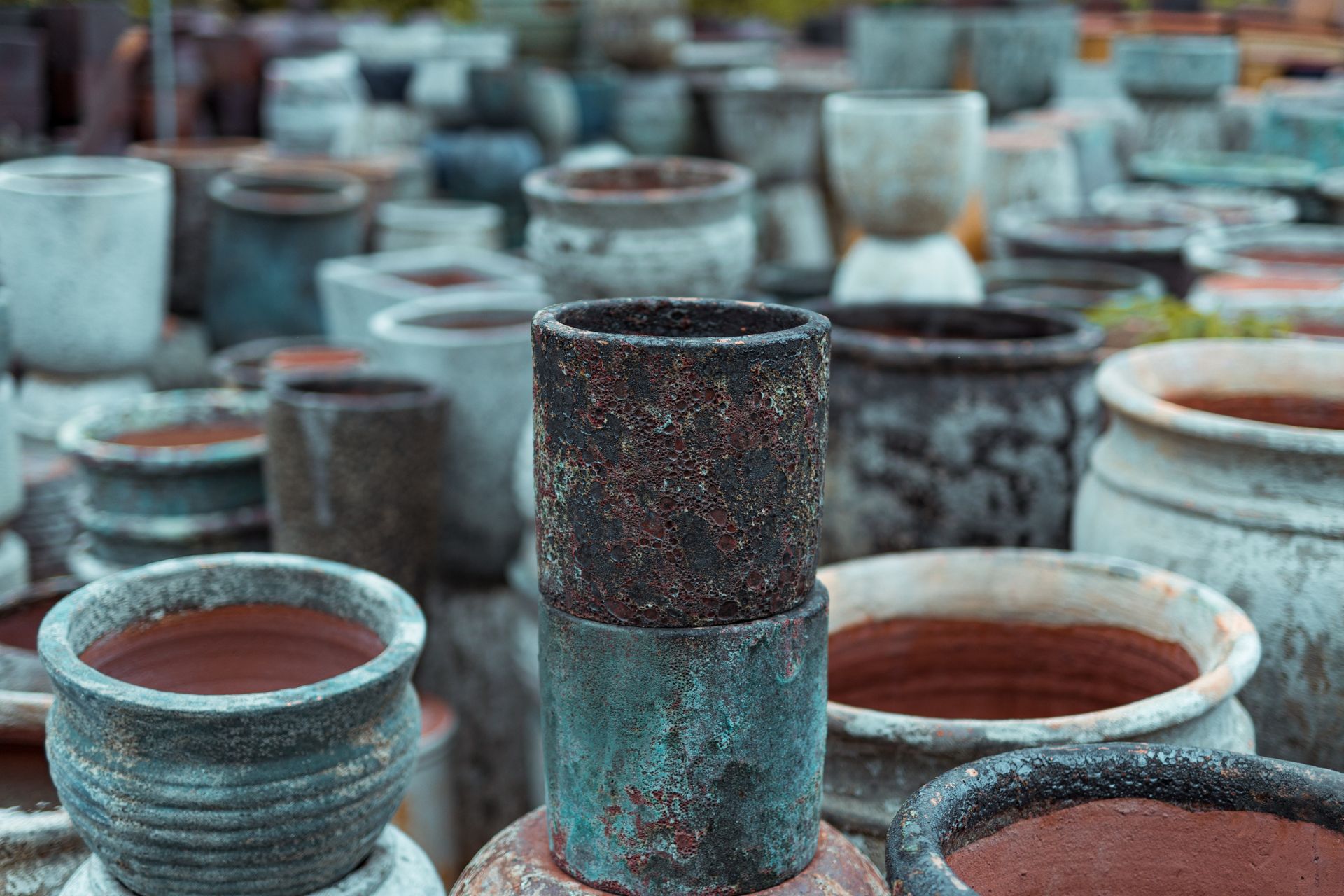 A variety of rustic ceramic pots displayed outdoors in Bien Hoa, Vietnam, showcasing diverse textures and colors.
