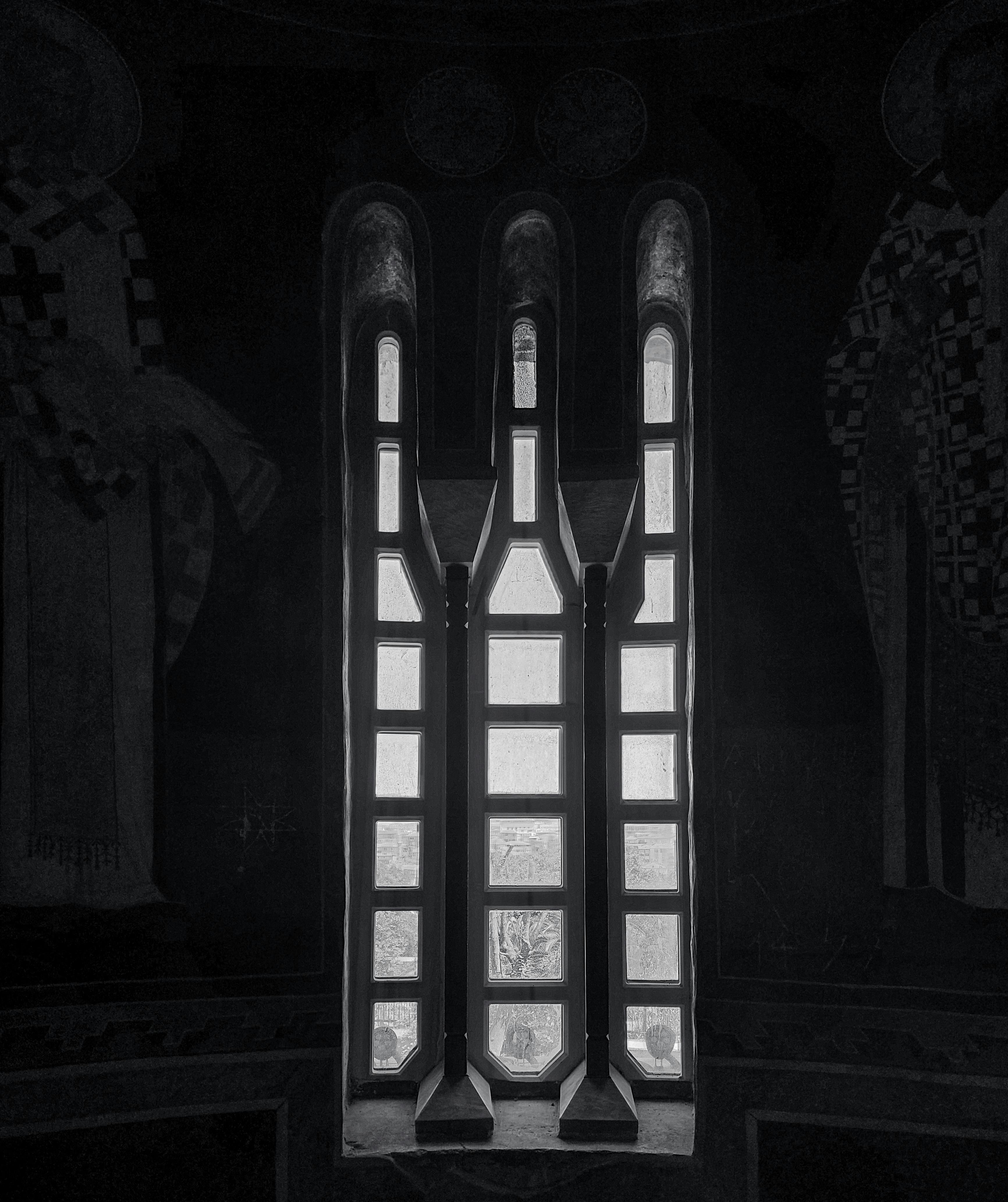 grátis Foto em preto e branco de uma janela de igreja gótica com afrescos ao redor, destacando detalhes arquitetônicos. Foto profissional