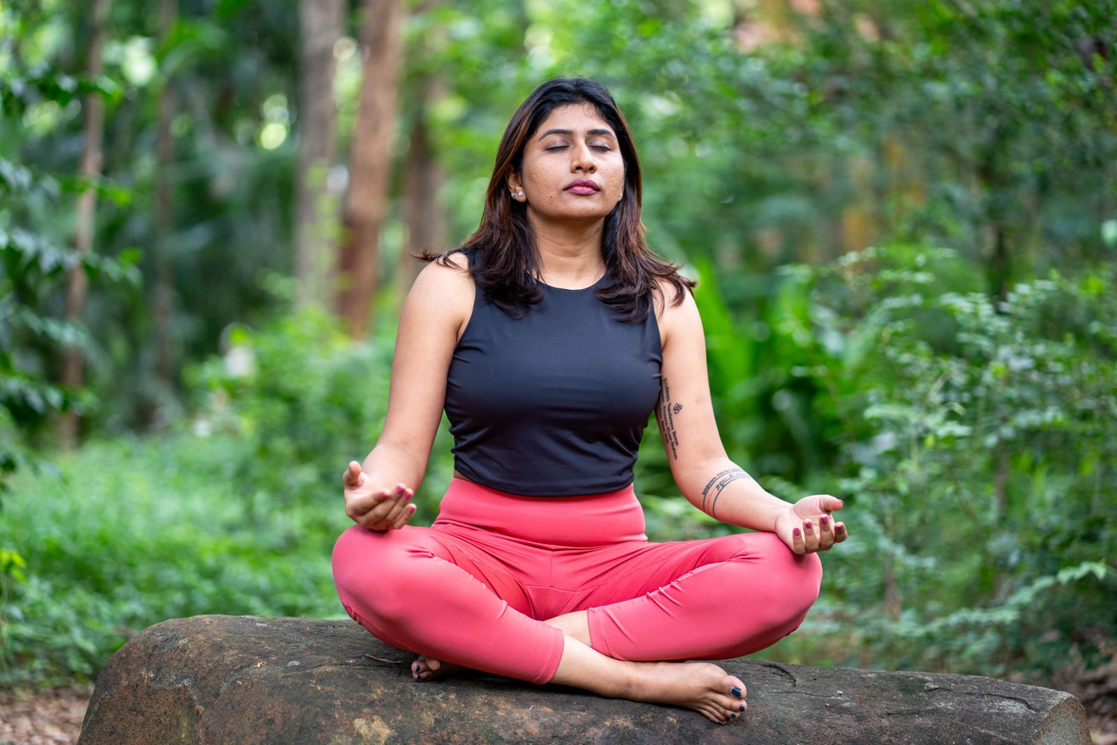 Woman practicing seated meditative yoga pose outdoors surrounded by greenery for diabetes wellness