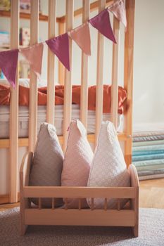 Warm nursery room with plush toy pillows, wooden crib, and decorative bunting.