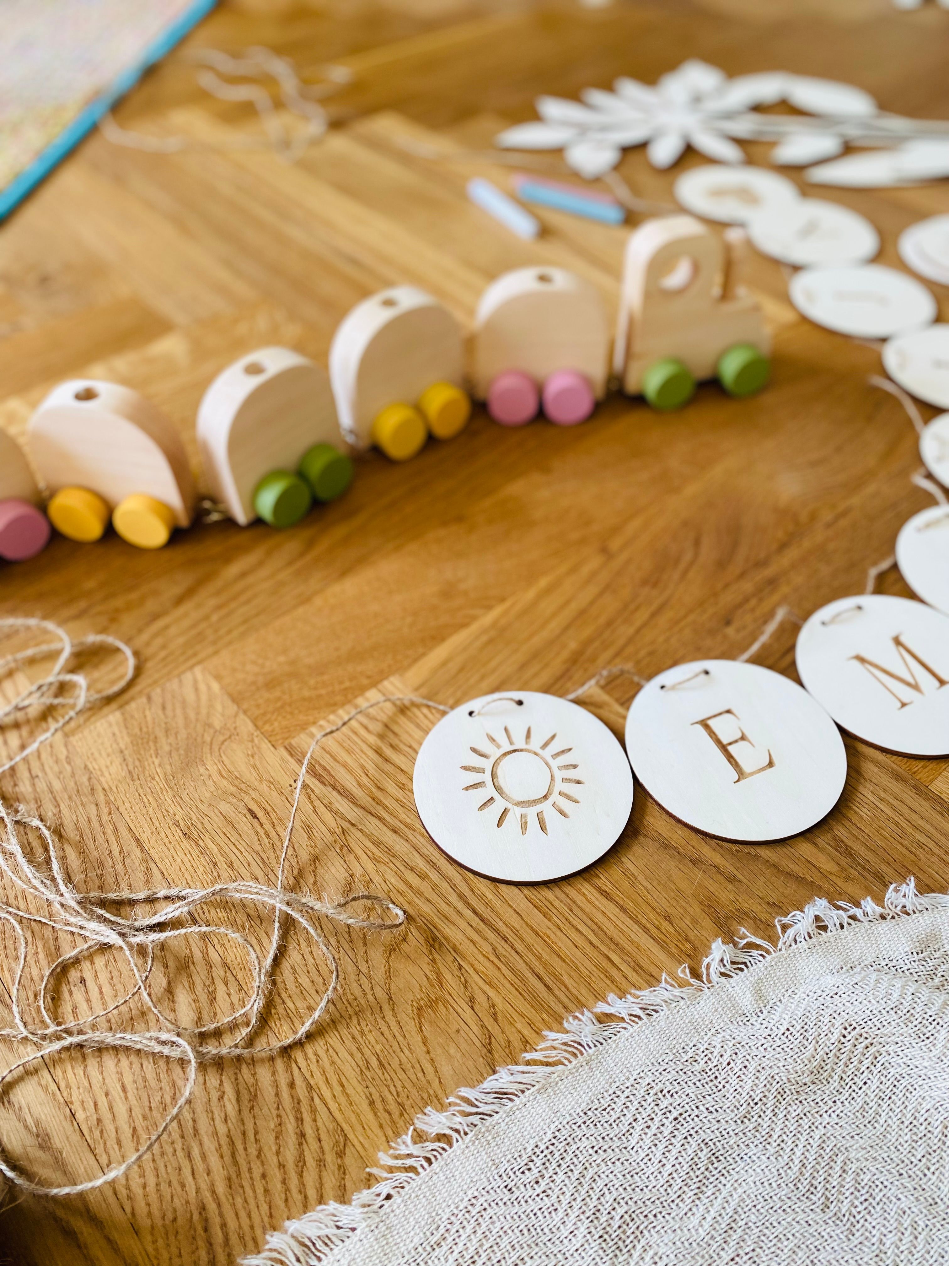 Natural wooden toy train and hanging ornaments on a wooden table, showcasing eco-friendly play.
