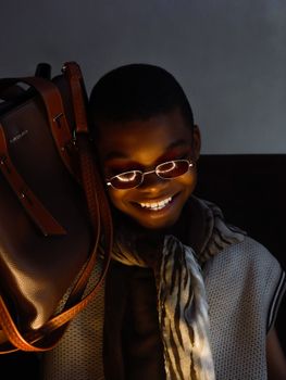 Stylish portrait of a smiling adult with fashionable accessories in low light.