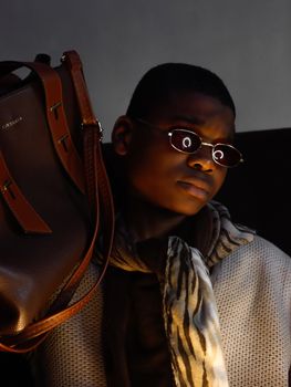 Elegant portrait featuring a man with luxury fashion accessories in moody lighting, emphasizing high fashion style.