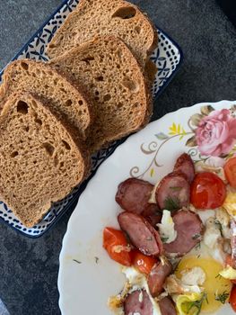 A hearty breakfast featuring sausage, egg, and fresh bread slices for a tasty start to the day.