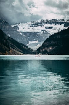 在戏剧性的天空和山脉映衬下，路易斯湖的壮丽景色中有一叶独木舟