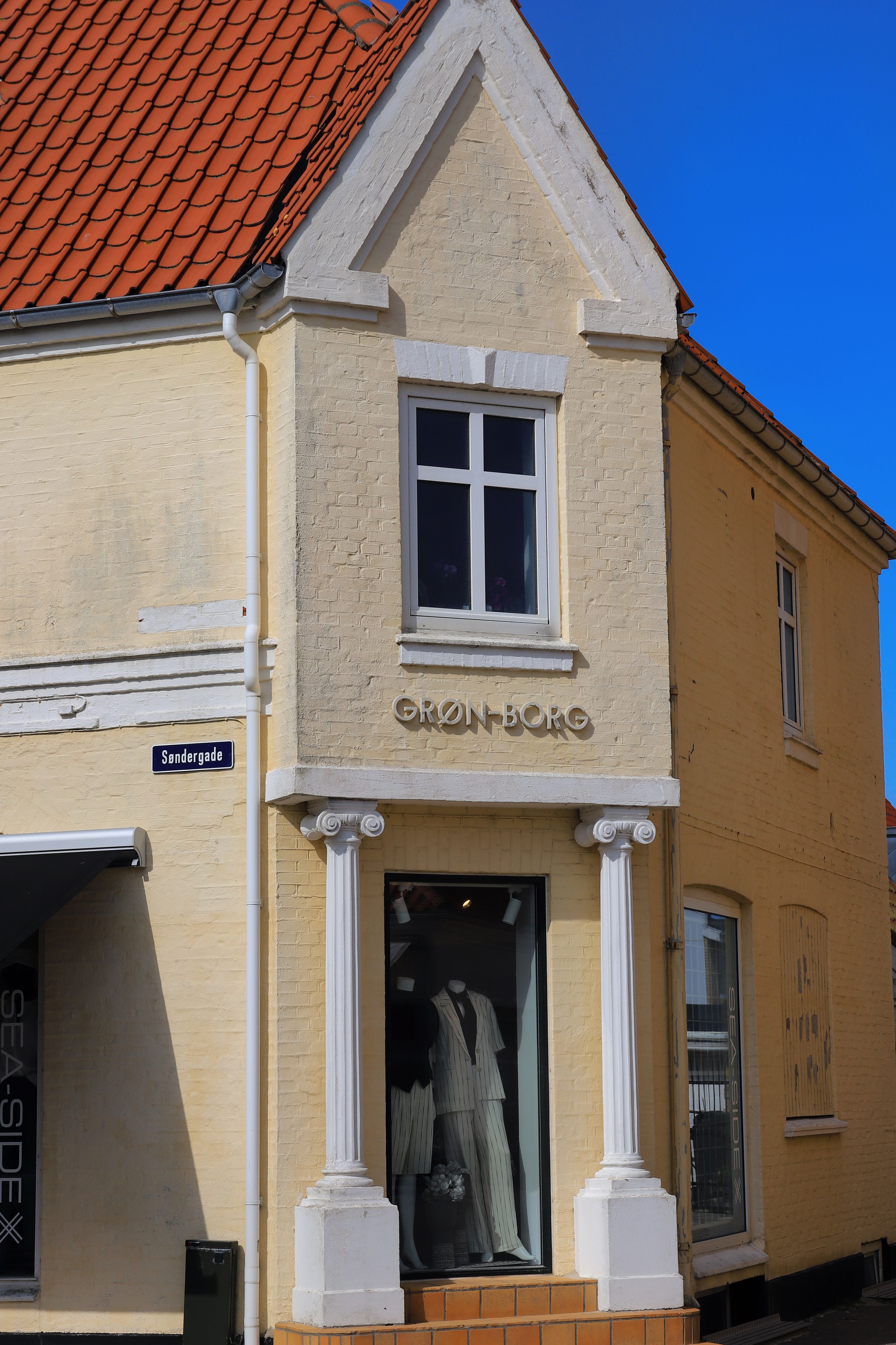 Charming street view of a classic building facade in Løkken, Denmark, with blue skies.