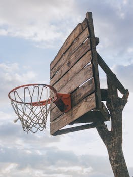 A rustic wooden basketball hoop stands tall against a cloudy sky. Perfect for sports and outdoor themes.