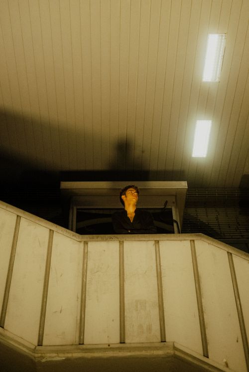 Free A man in a black shirt poses indoors under dramatic artificial lighting, creating a moody ambiance. Stock Photo