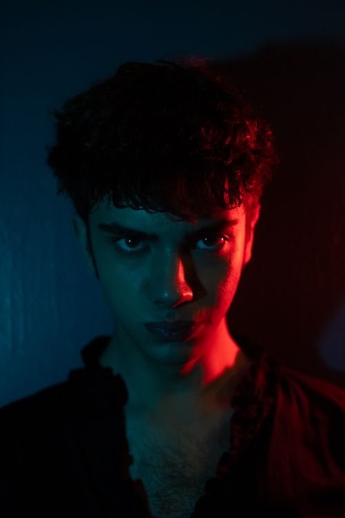 Free A striking portrait of a man with intense lighting effects in red and blue creating a moody atmosphere. Stock Photo