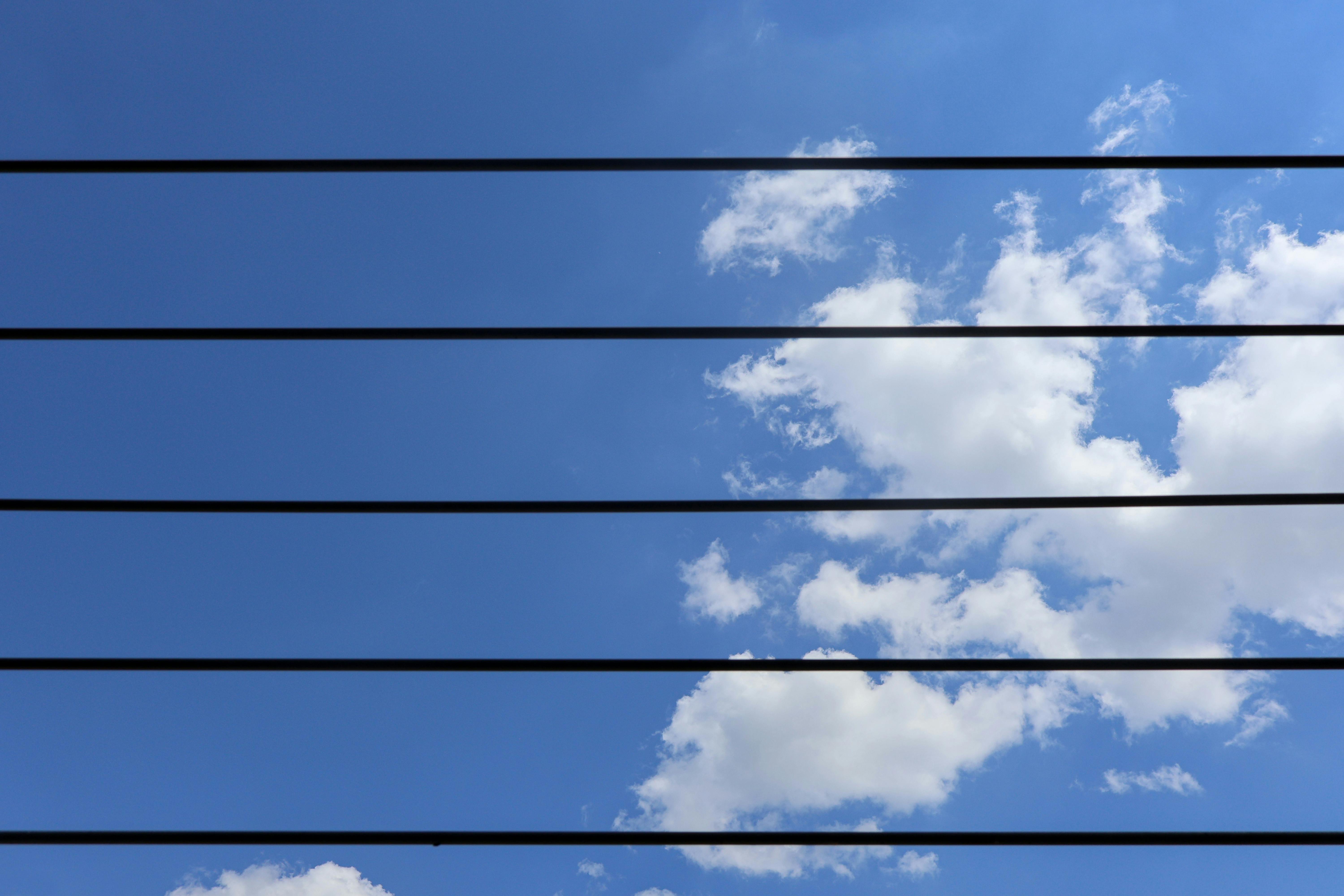 Kostenlos Stromleitungen durchqueren einen klaren blauen Himmel mit flauschigen Wolken in Mailand, Italien. Stock-Foto