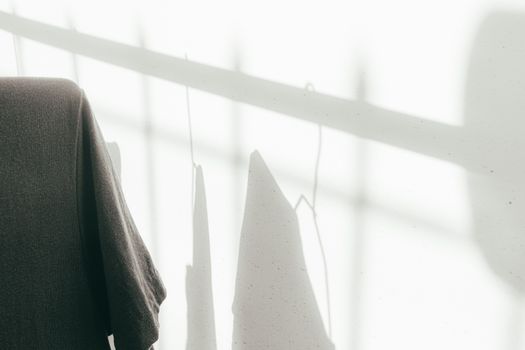 Minimalist photo of hanging clothes casting shadows on a sunlit wall