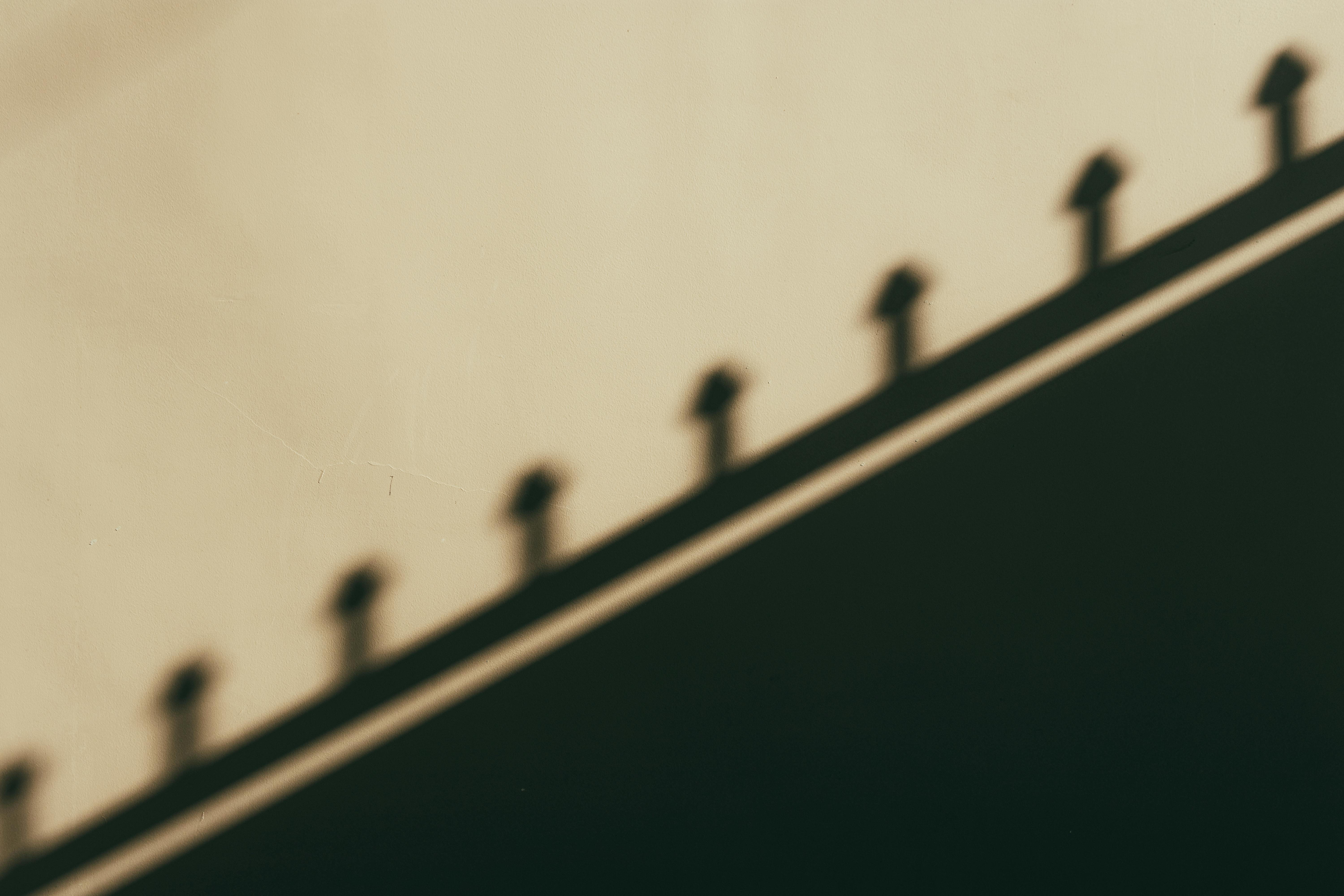 Free Artistic shadow of railing cast on a beige wall creating a minimalist pattern. Stock Photo