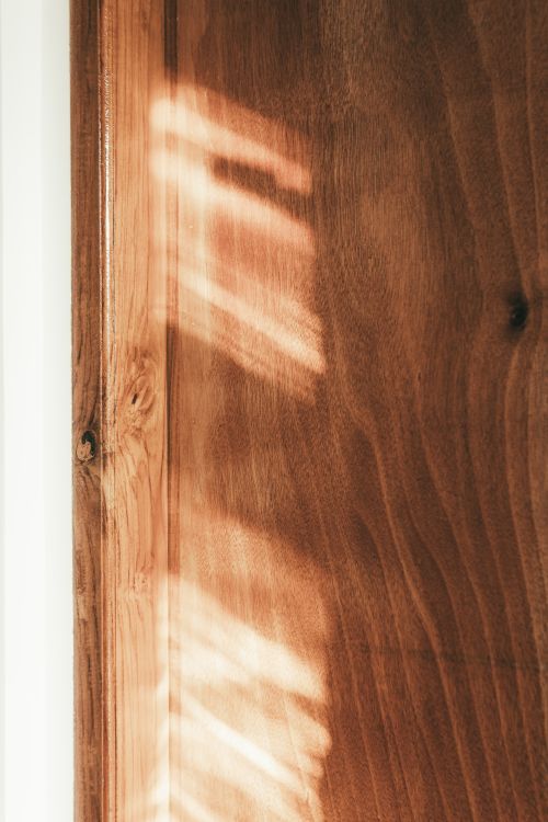 Free Sunlight casting natural patterns on a wooden door, creating a warm and rustic ambiance. Stock Photo