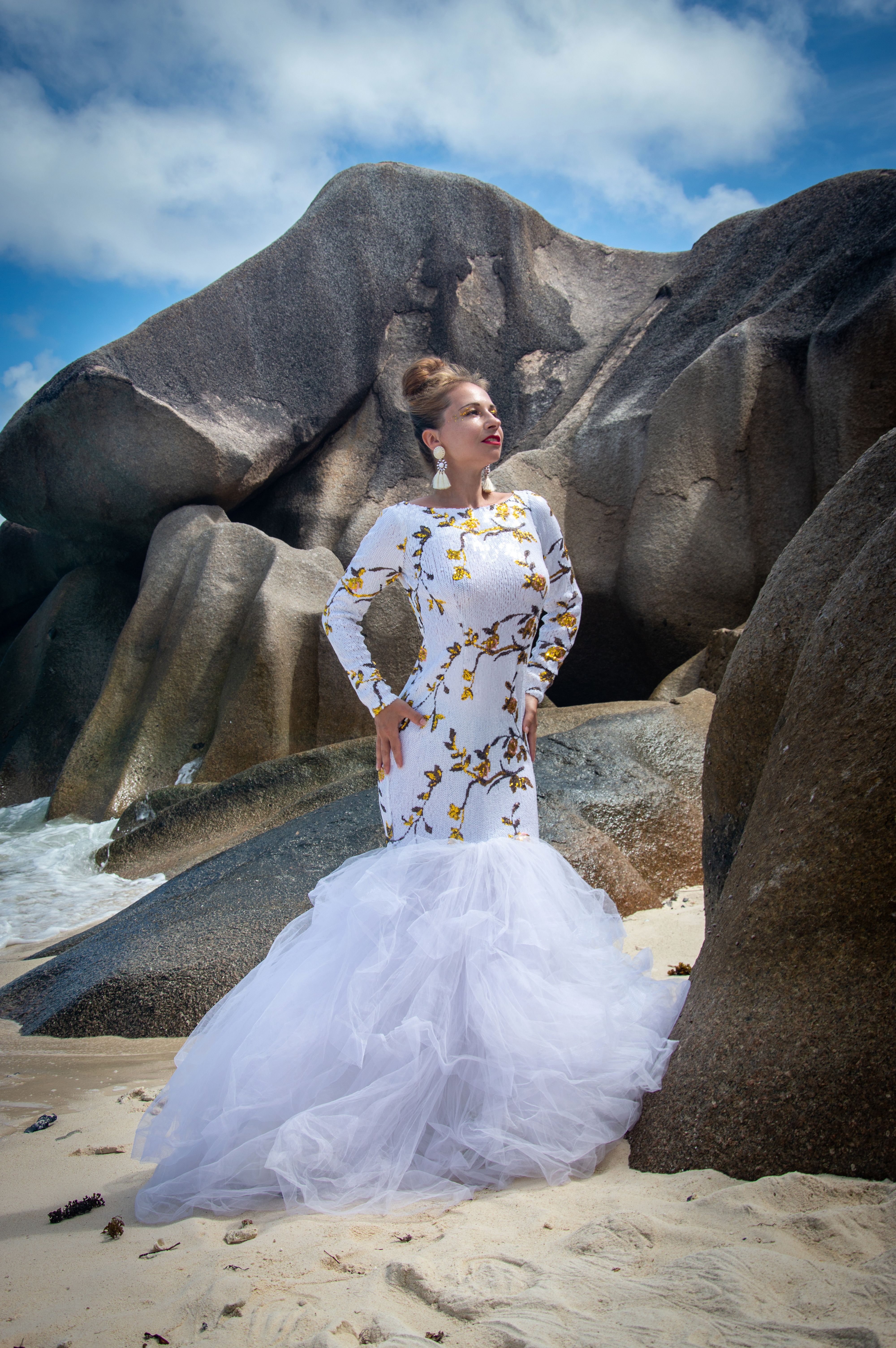 Elegant woman in floral dress on rocky beach, Seychelles