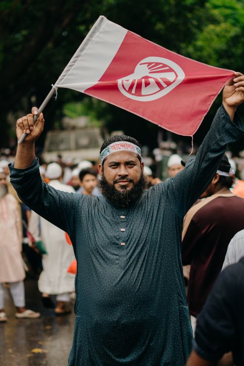 Free A man in traditional attire holds a flag at an outdoor gathering, exuding cultural pride. Stock Photo