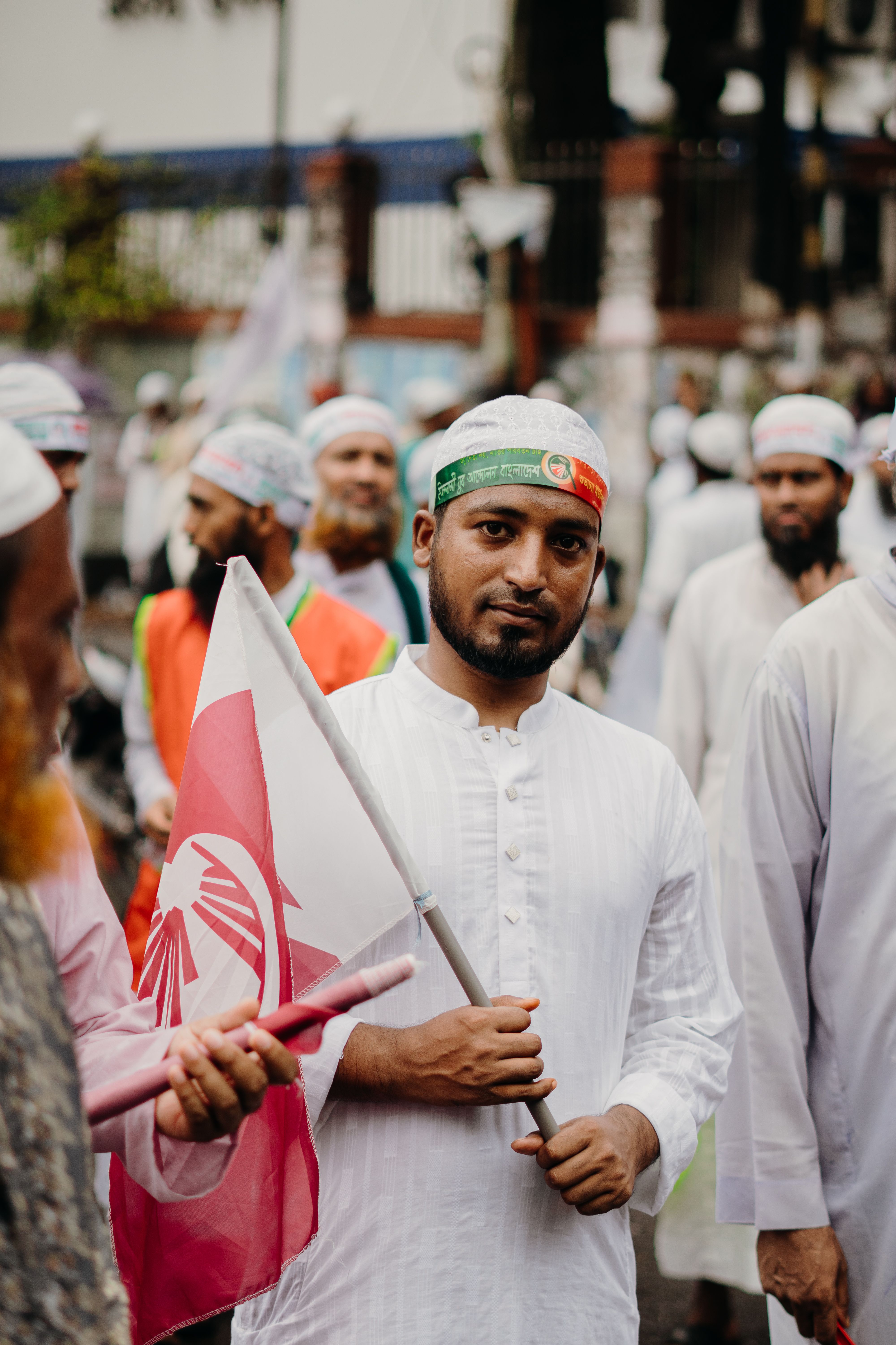 A man in traditional attire holds a flag during a cultural parade, showcasing vibrant diversity.