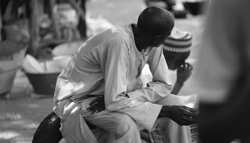 Free Black and white image of two men in traditional attire sitting outdoors, capturing a candid moment. Stock Photo