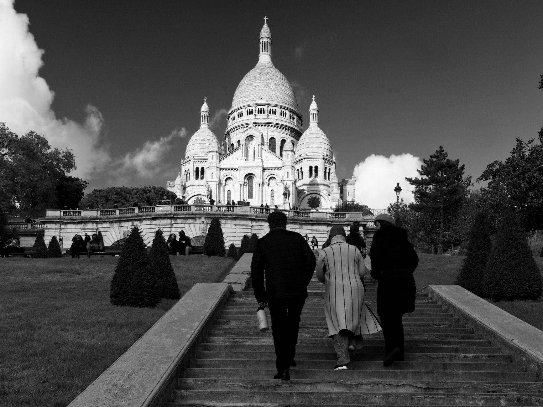Black and white image of people walking up steps to Sacré-Cœur Basilica in Paris.
