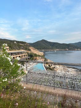 Beautiful coastal resort overlooking a pool with mountain views and clear skies.