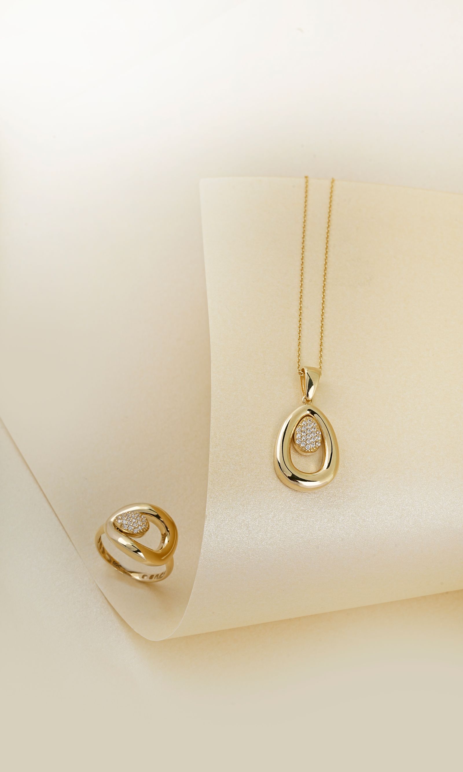 Elegant gold necklace and ring on cream background