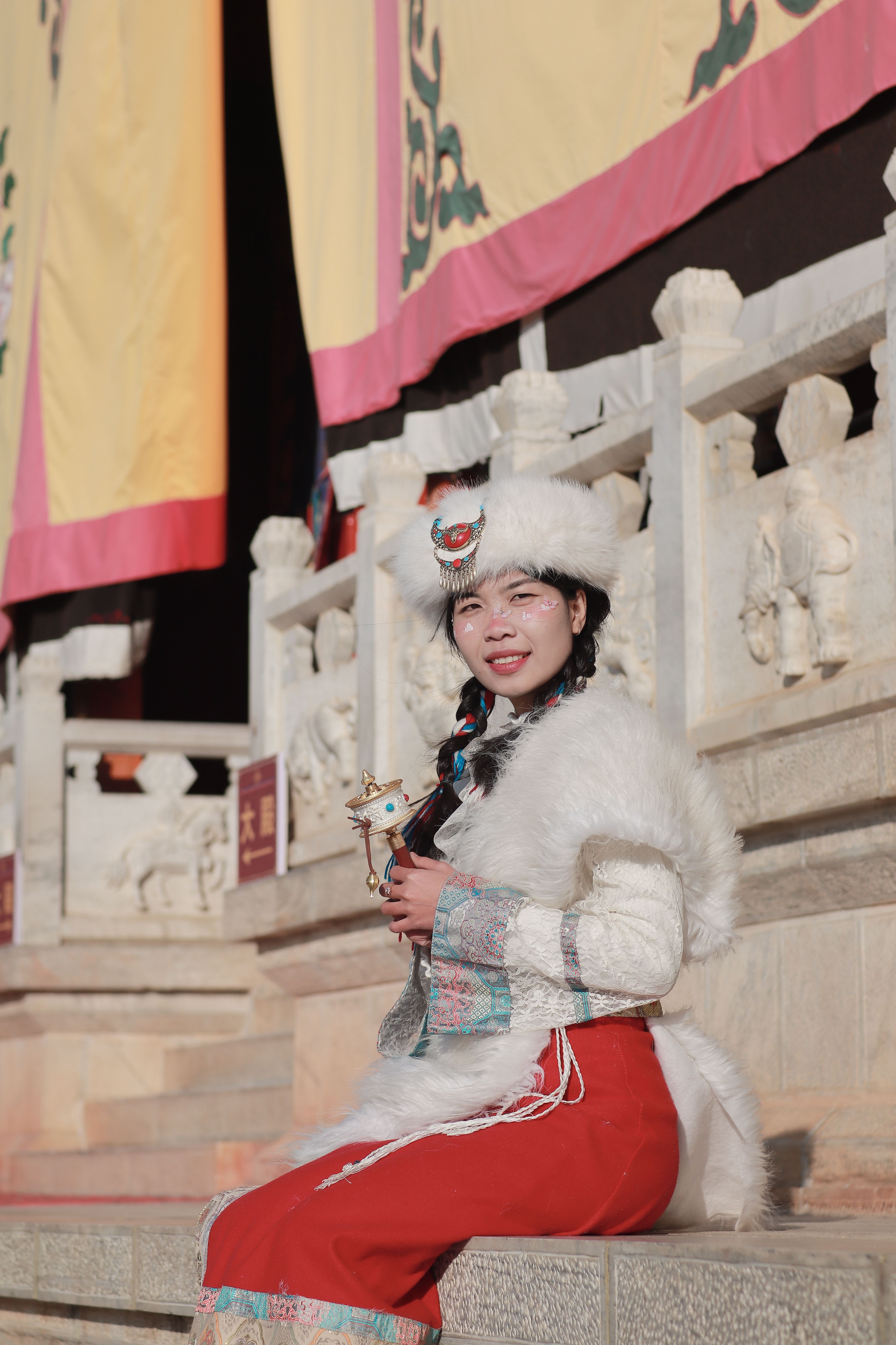 A woman in traditional clothing poses outdoors by a historic structure, exuding cultural charm.