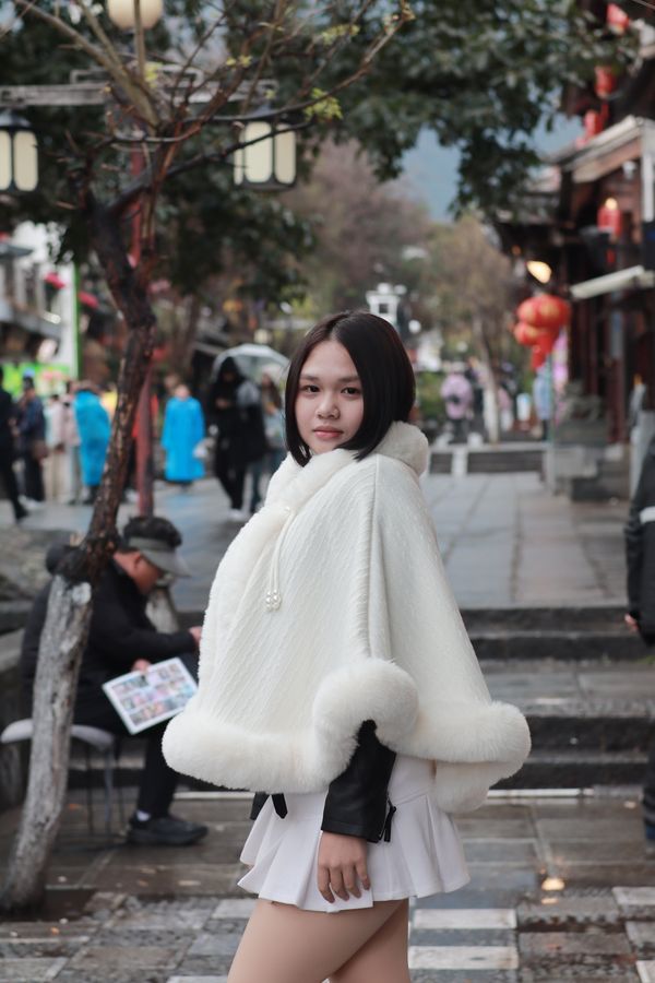Woman in white cape on cobblestone street