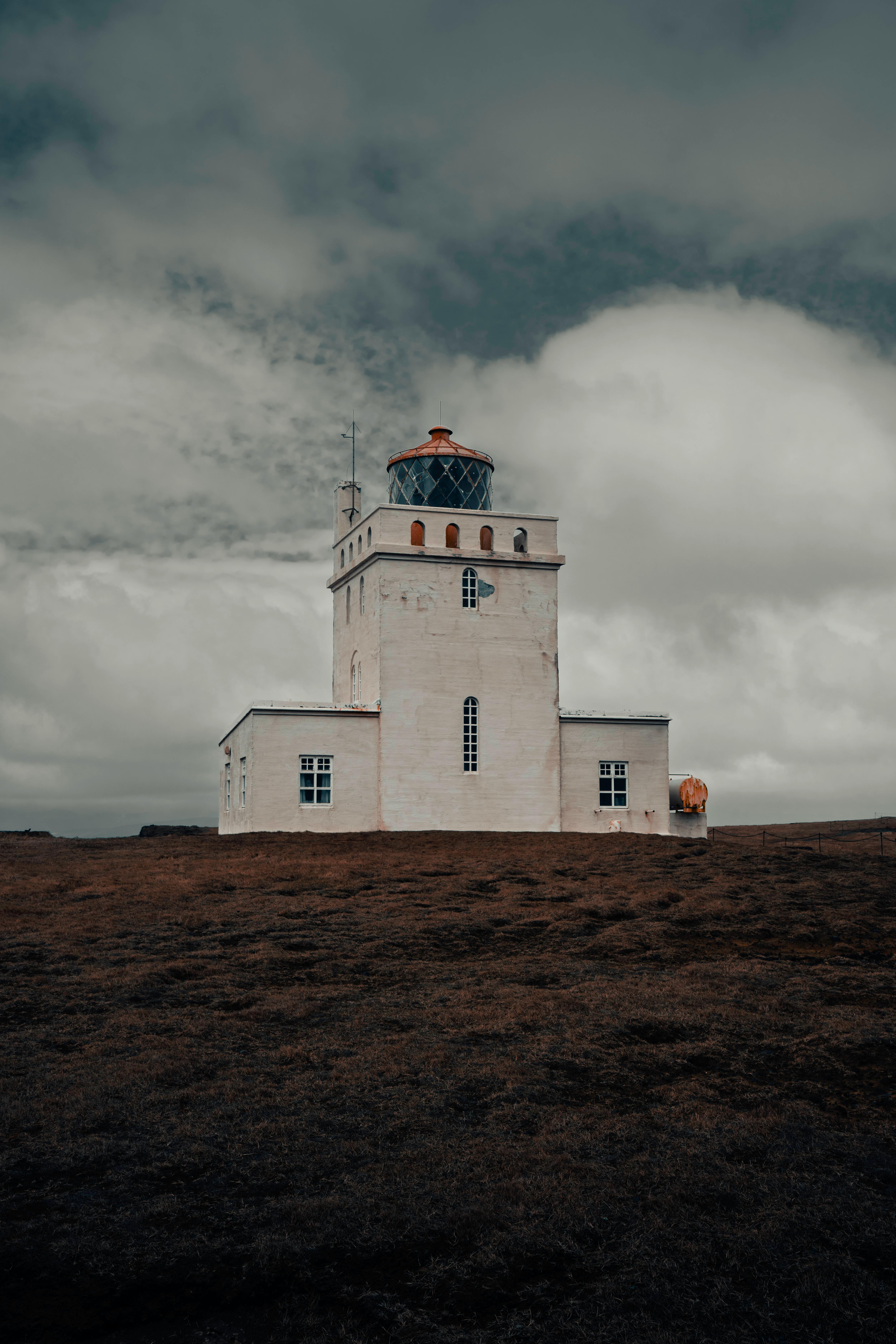 A stunning white lighthouse under a dramatic Icelandic sky, showcasing rugged tranquility.