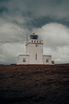 A stunning white lighthouse under a dramatic Icelandic sky, showcasing rugged tranquility.