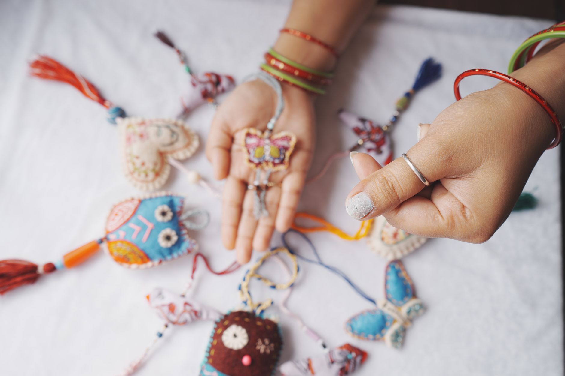 Vibrant handmade fabric ornaments including butterflies and hearts on display with hands holding them.