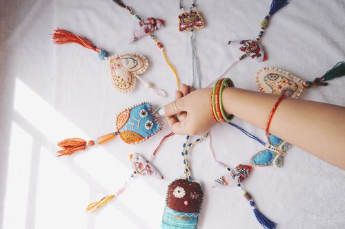 Free A woman's hand arranging colorful handmade ornaments on a white background Stock Photo