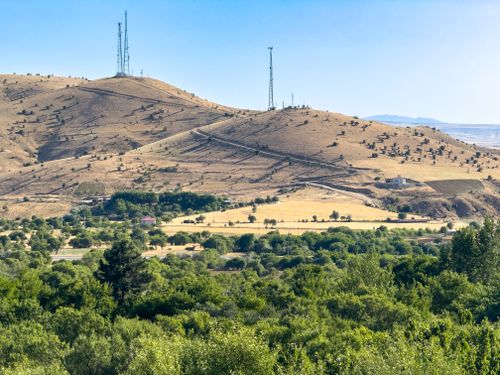 Free Scenic view of green valley and dry hills with antenna towers in Pertek, Türkiye. Stock Photo