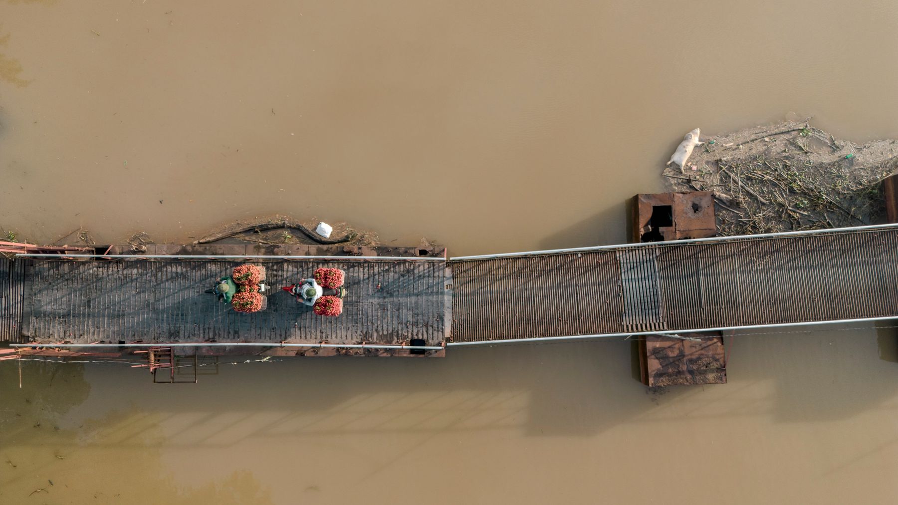 Aerial shot of a bridge in Bac Giang, Vietnam, showcasing traditional lychee transport across the river.