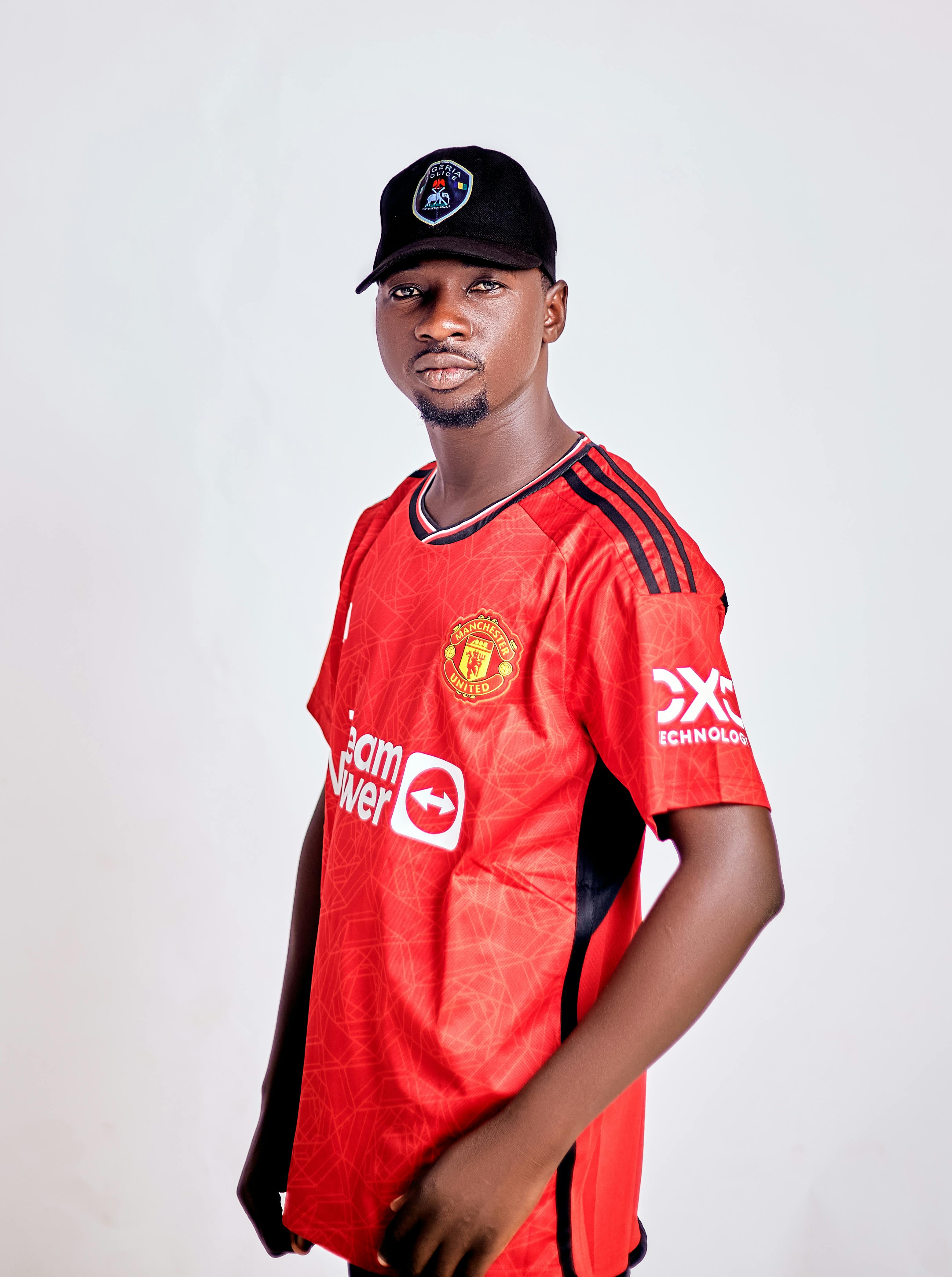 Portrait of a man wearing a red sports jersey and black cap, exuding confidence.