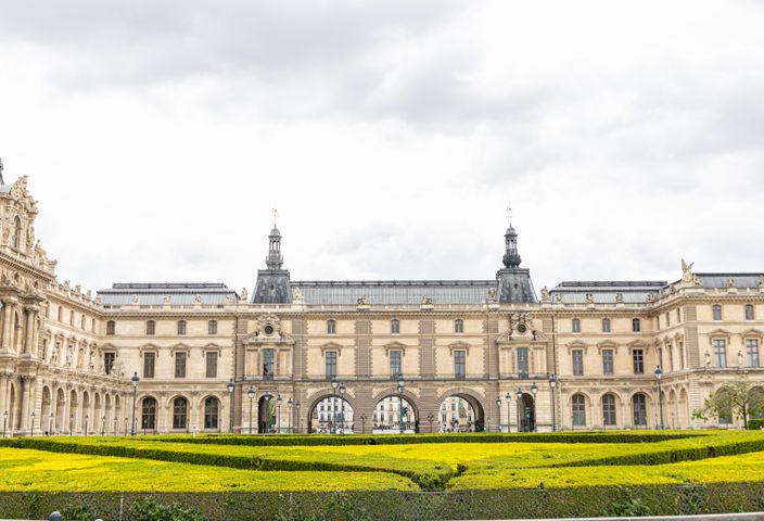 The Louvre Museum's classic architecture under a cloudy sky in Paris captures timeless elegance.
