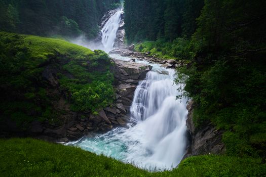 Stunning view of Krimml Waterfalls cascading through lush greenery in summer.