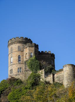 Majestic fortress tower in Edinburgh against a clear blue sky, showcasing historic architecture.