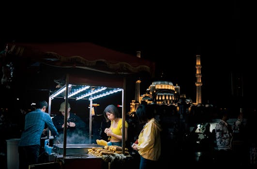 Enjoy the allure of Turkish street food at night, with a bustling vendor near a majestic mosque in Istanbul.